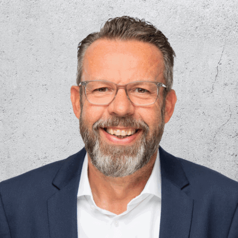 Lächelnder Mann mit Brille und Bart im Anzug